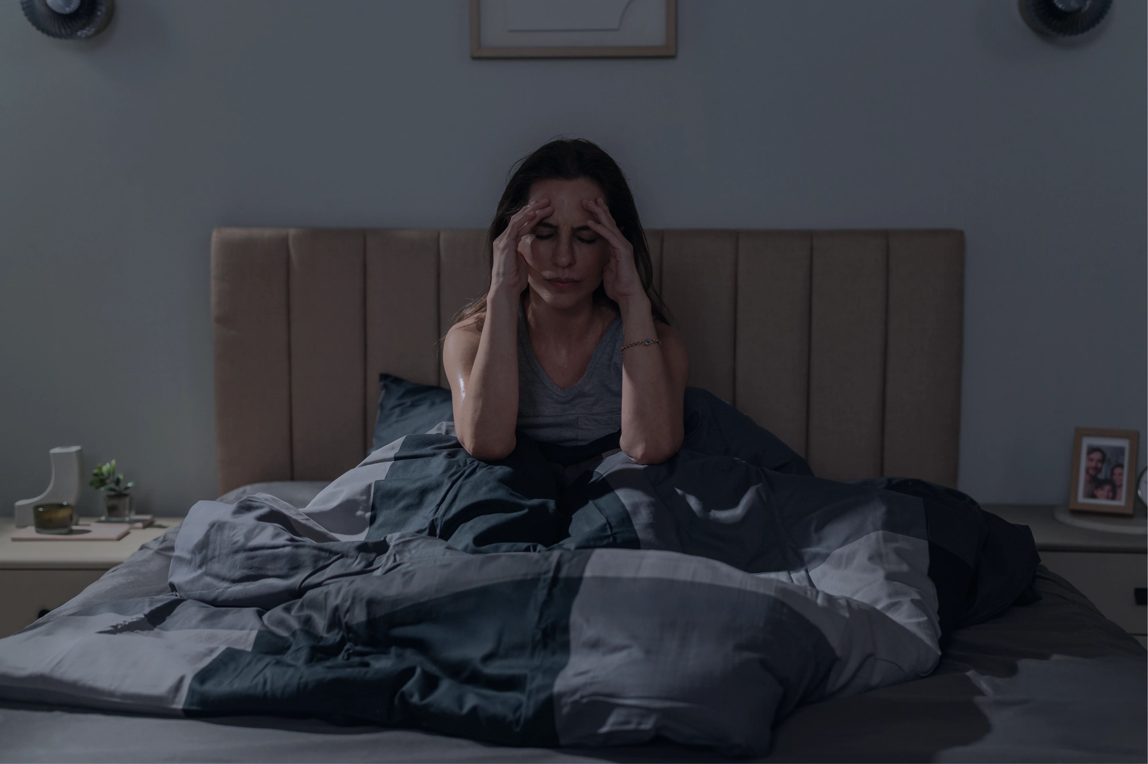 Woman awake in bed at night, hands to her temples